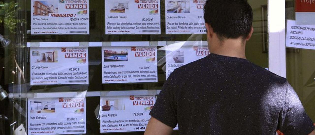 Un joven obsserva ofertas en una inmobiliaria.