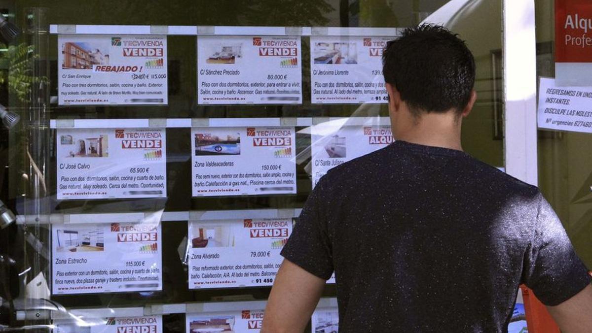 Un joven obsserva ofertas en una inmobiliaria. Un joven obsserva ofertas en una inmobiliaria.