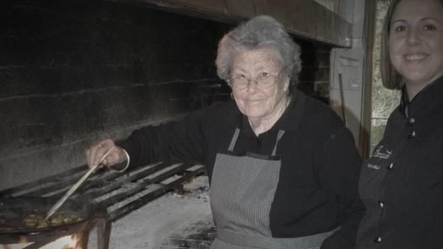 Teresa Antón Agulló cocinando una paella en su restaurante con su nieta Silvia.