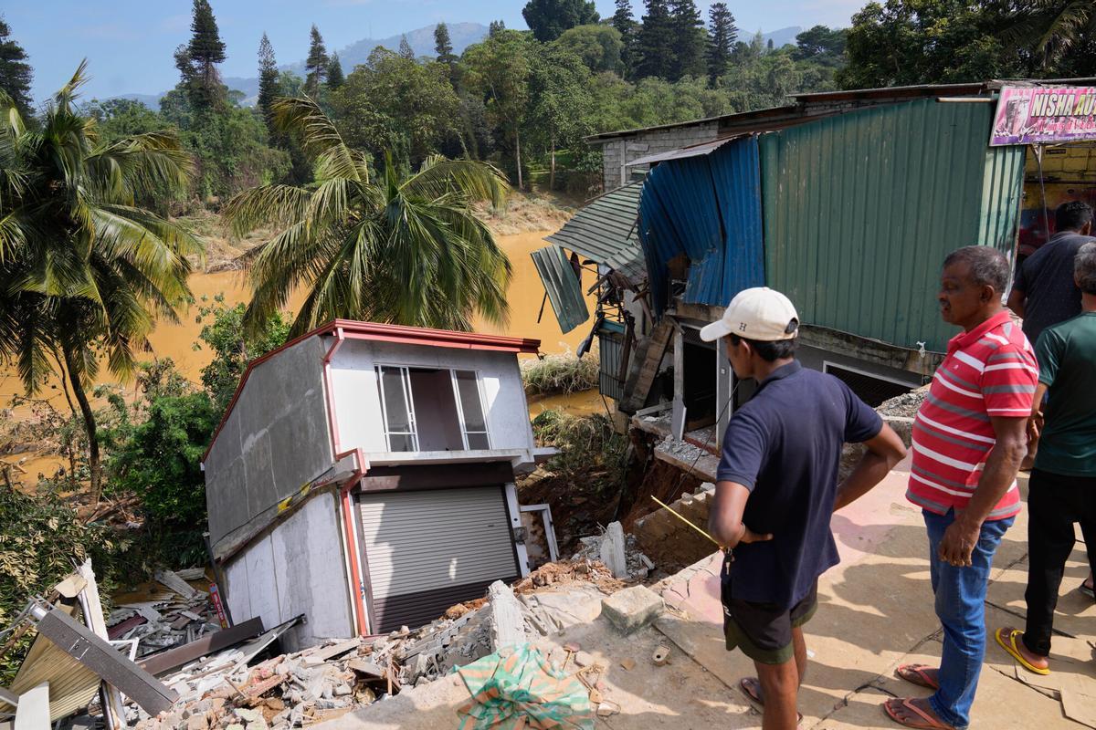 People look at a building damaged by the floods in Peradeniya, Sri Lanka, Monday, Dec. 1,2025. (AP Photo/Eranga Jayawardena)