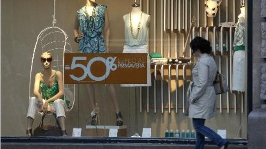 Una joven pasa ante un escaparate de un comercio de Valencia con descuentos de hasta el 50 %.