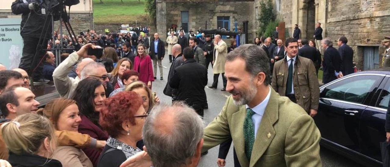 El Rey (y al fondo, la Reina) saludando el pasado sábado a los vecinos frente al monasterio de Villanueva, una de las joyas turísticas de la comarca de los Oscos.