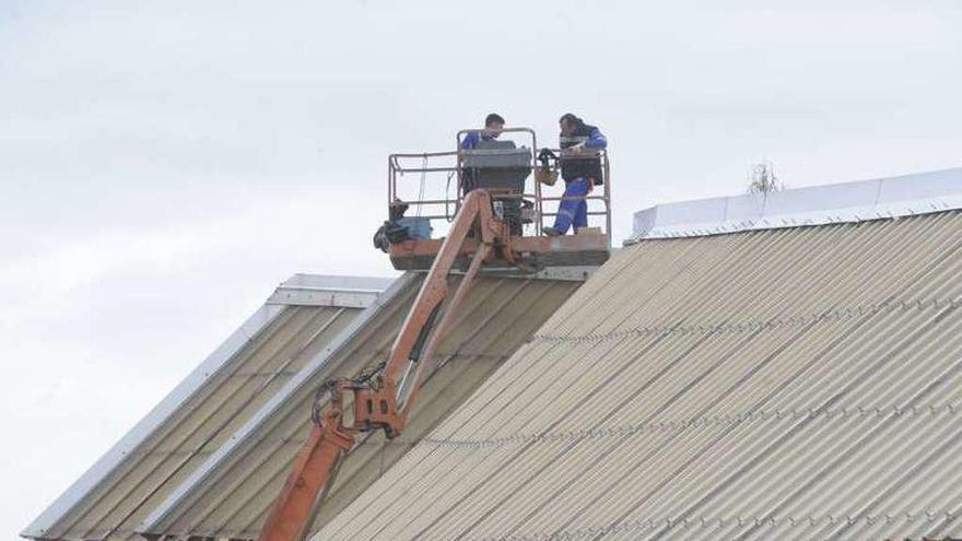 Operarios en una grúa reparan una cubierta de Riazor.