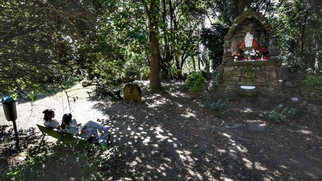 Dos trabajadoras del Monte Naranco, ante la réplica de la Santina en los jardines del hospital. | MIKI LÓPEZ