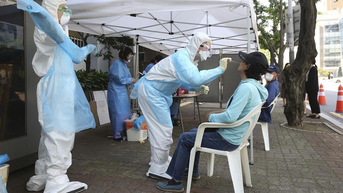 Un sanitario realiza un prueba de covid-19 a una mujer en un hospital de Seúl, este viernes.