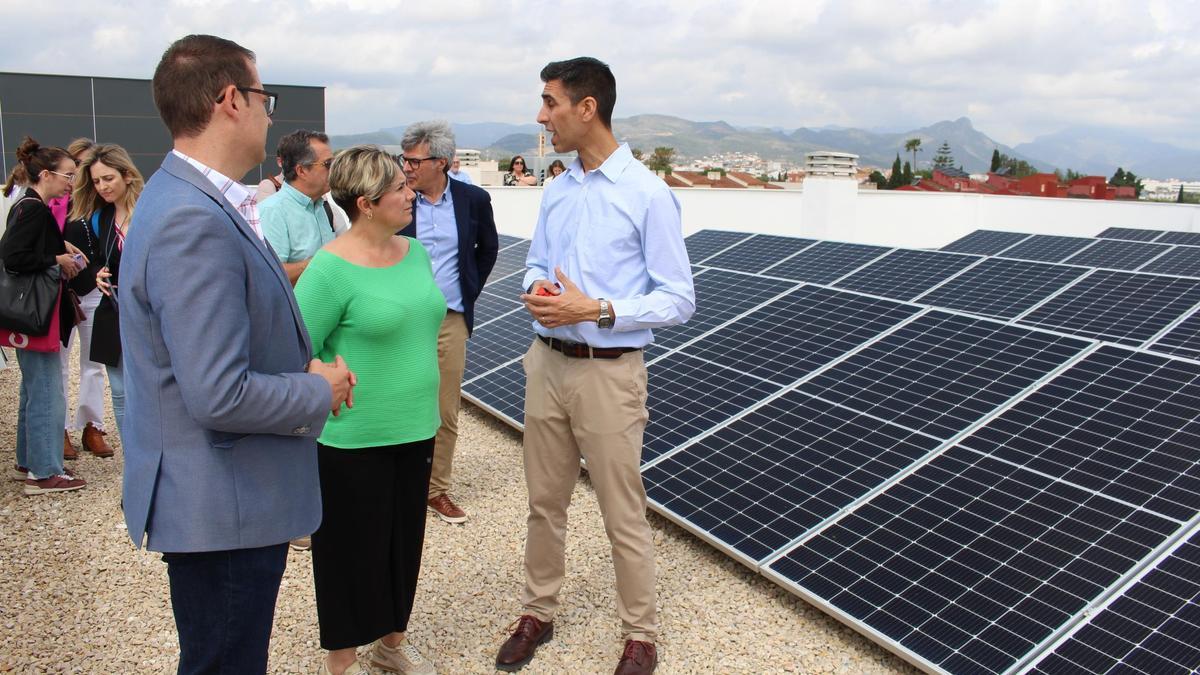 La consellera, junto al alcalde y otras personas, en la terraza del colegio, lleno de placas fotovoltaicas.