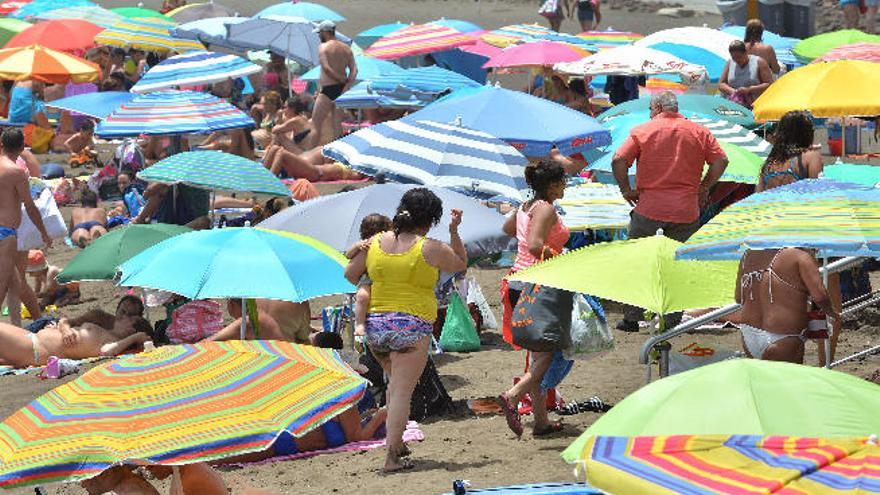 Melenara, ayer, lleno de sombrillas y con varias personas marchándose por el fuerte calor.