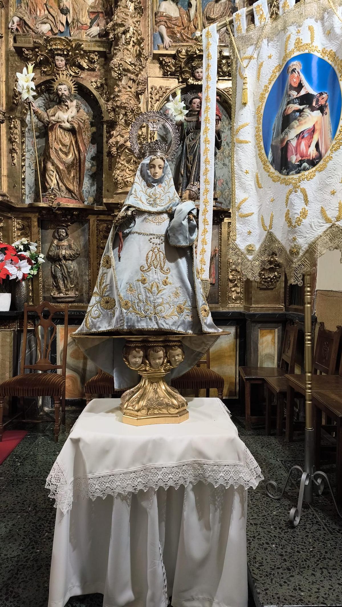 En el centro, la imagen de la Santina trasladada desde La Isla, en la iglesia de Pobladura de Pelayo García junto a un estandarte con la imagen de la Virgen de las Angustias.