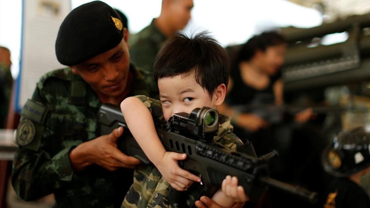 Un soldado tailandés muestra a un niño cómo funciona un arma en la celebración del Día del Niño.