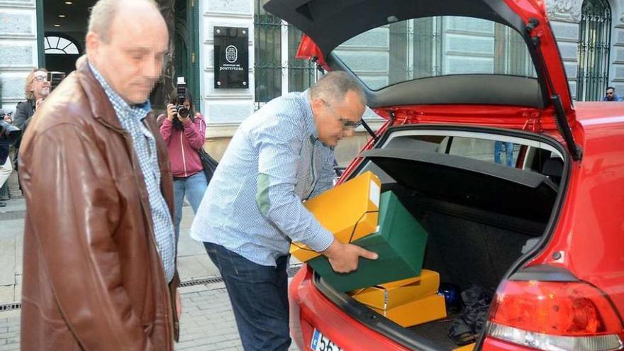 Dos agentes introducen cajas y carpetas en un coche, ayer ante el Concello de Pontevedra. // Rafa Vázquez