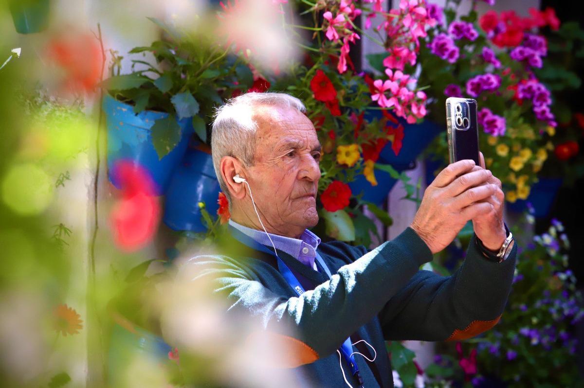 Un hombre toma una fotografía con el móvil en el patio de la calle Tinte.