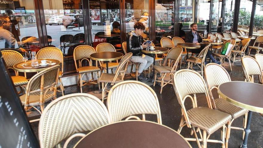 Varias personas en una terraza semivacía en París.