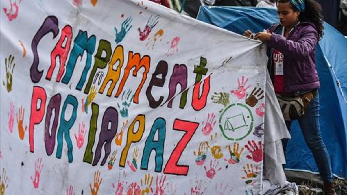 Una joven ayuda a colocar una pancarta a favor del acuerdo de paz en una acampada en Bogotá.