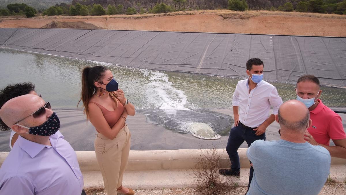 La consellera Mireia Mollà conversa con los regantes mientras el agua entra en el embalse esta mañana