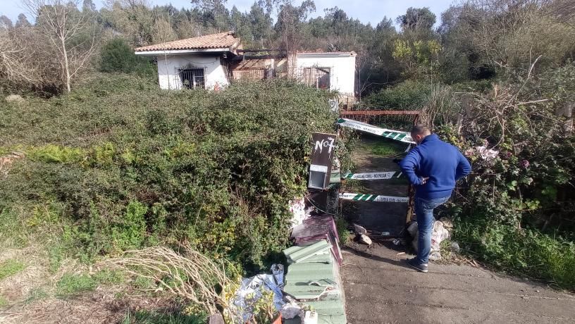 Un hombre junto a la entrada de la vivienda que ardió el martes, precintada por la Guardia Civil para investigar el incendio.