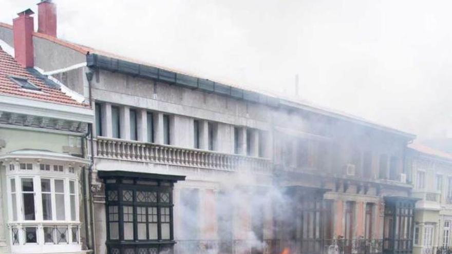 Un bombero y varios camiones, durante la extinción del incendio en el número 58 de la calle Uría.