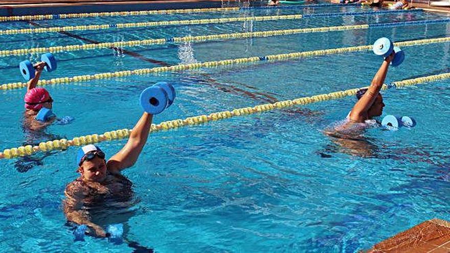 Tres mujeres hacen aquagym con mancuernas en las Piscinas Municipales de Benavente.