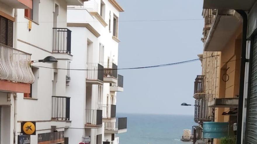 Un dels carrers del centre de l&#039;Escala ben moll aquest matí i la mar plana al fons