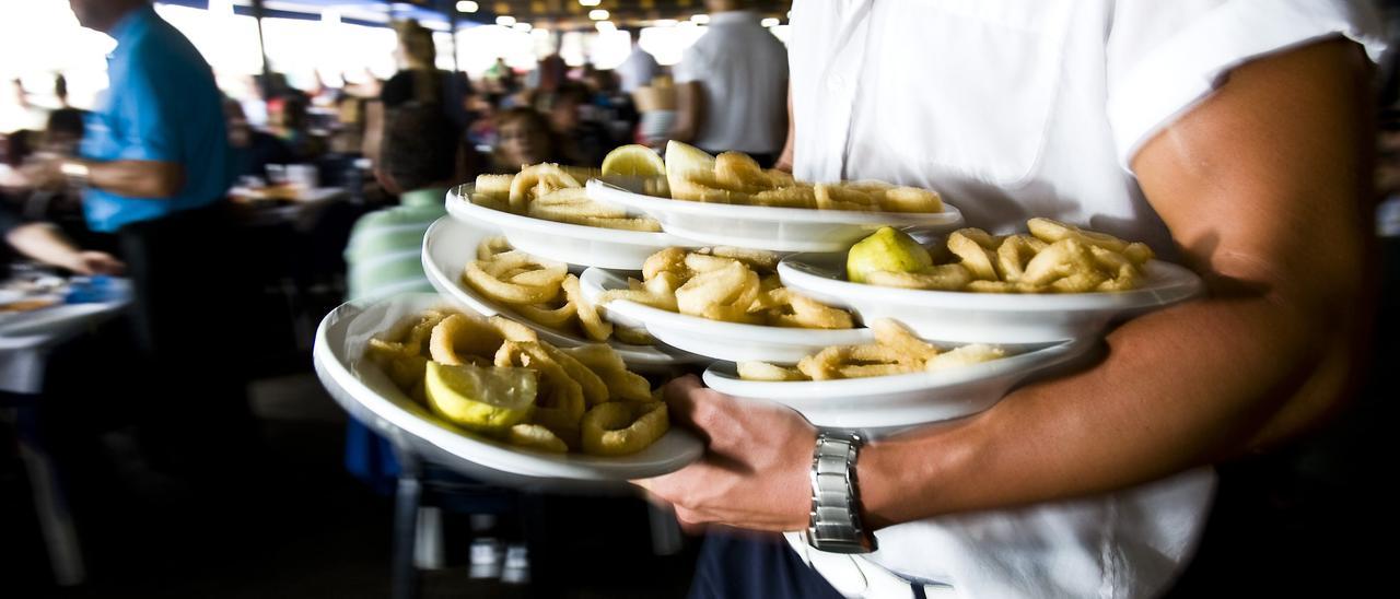 Un camarero con varios platos para servir una mesa. // Jorge Zapata