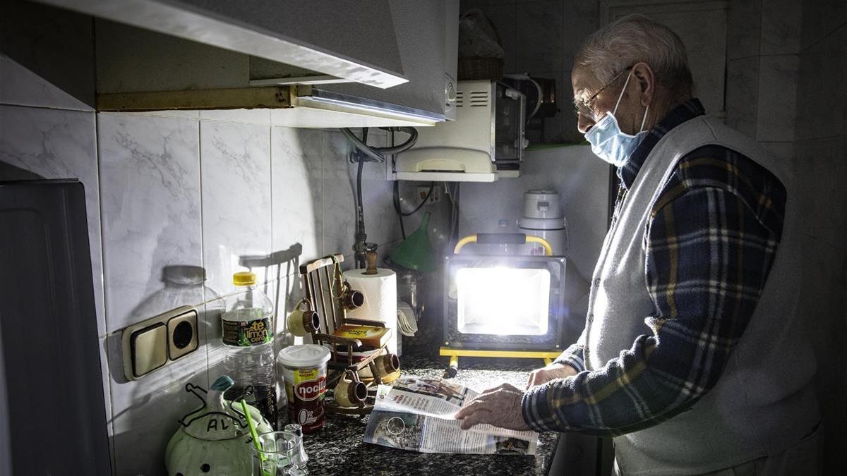 Juan Pérez se ayuda de linternas y un foco a pilas para orientarse en su casa de los cortes de luz que sufre el barrio del Culubret, de Figueres.
