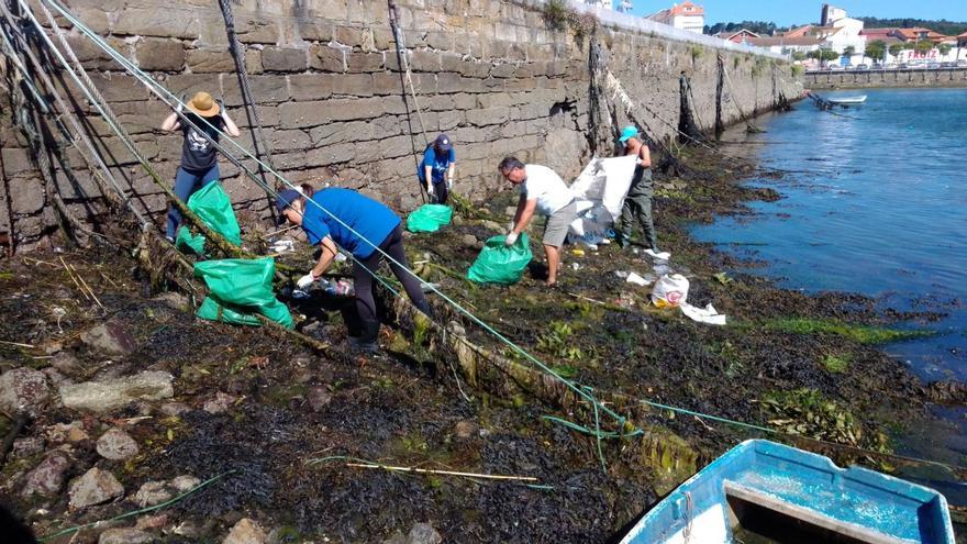 Voluntarios convocados por Mar de Fábula recollendo o lixo acumulado no porto de Camariñas despois das festas do Carme /MAR DE FÁBULA