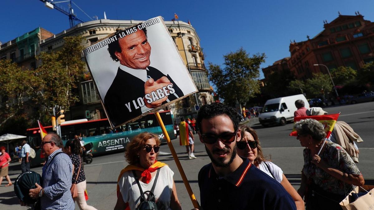 A man carries a sign depicting Spanish singer Julio Iglesias which reads &quot;Puigdemont you messed up and you know it&quot;  as demonstrators gathered for a pro-union demonstration organised by the Catalan Civil Society organisation in Barcelona