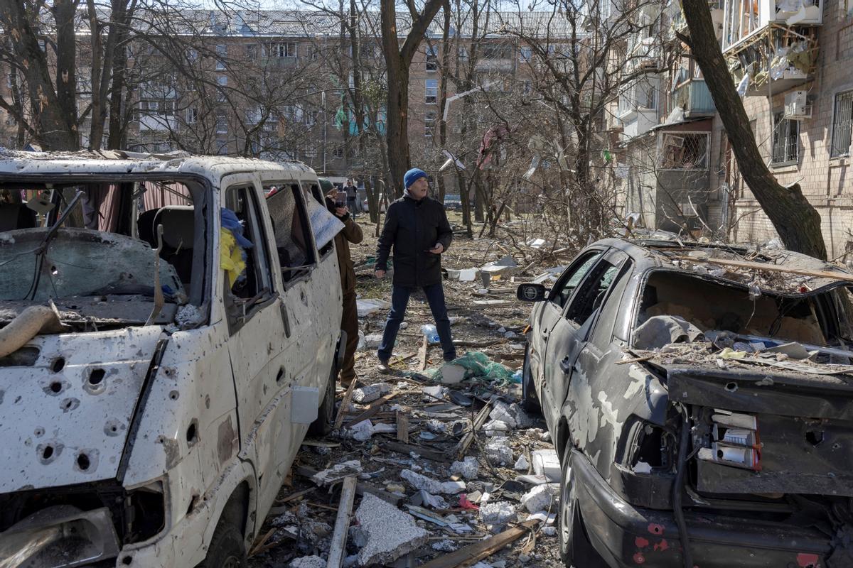 Un hombre camina junto a coches destruidos en un barrio residencial de Kiev, este viernes.