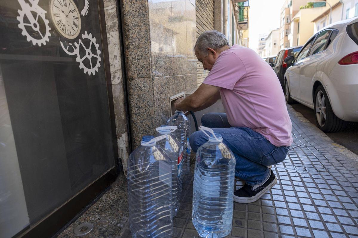 Uno de los inquilinos llena garrafas en un punto de Emaya a pocos metros de su casa.