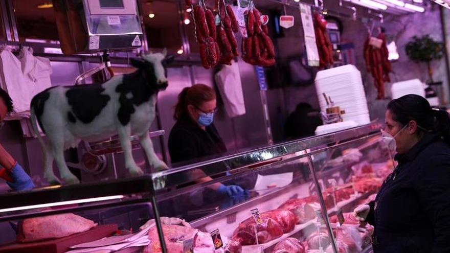 Dos empleats d&#039;una carnisseria atenent una clienta en un mercat de Madrid