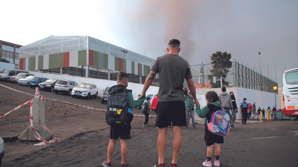 Un padre con sus dos hijos en el municipio palmero de El Paso durante la erupción del volcán de La Palma.