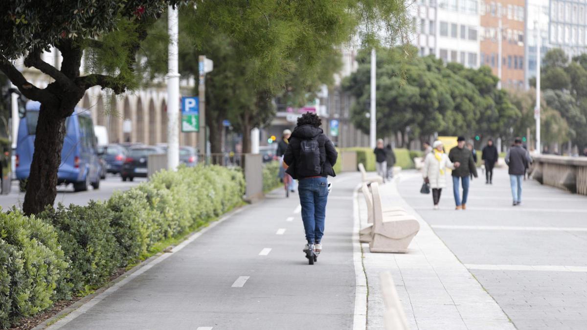 Un conductor con patinete eléctrico por el paseo marítimo de A Coruña.