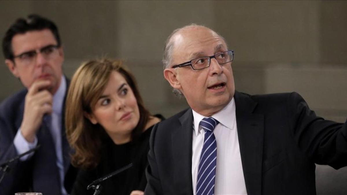 Los ministros José Manuel Soria y Cirstóbal Montoro y la vicepresidenta, Soraya Sáenz de Santamaría, en la rueda de prensa posterior al Consejo de Ministros.