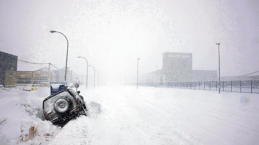 Un vehículo semienterrado en la nieve en una calle del pueblo palentino de Aguilar de Campoo.