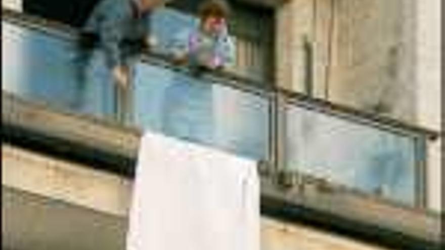 Gente colocando sábanas blancas en los balcones. / iñaki abella