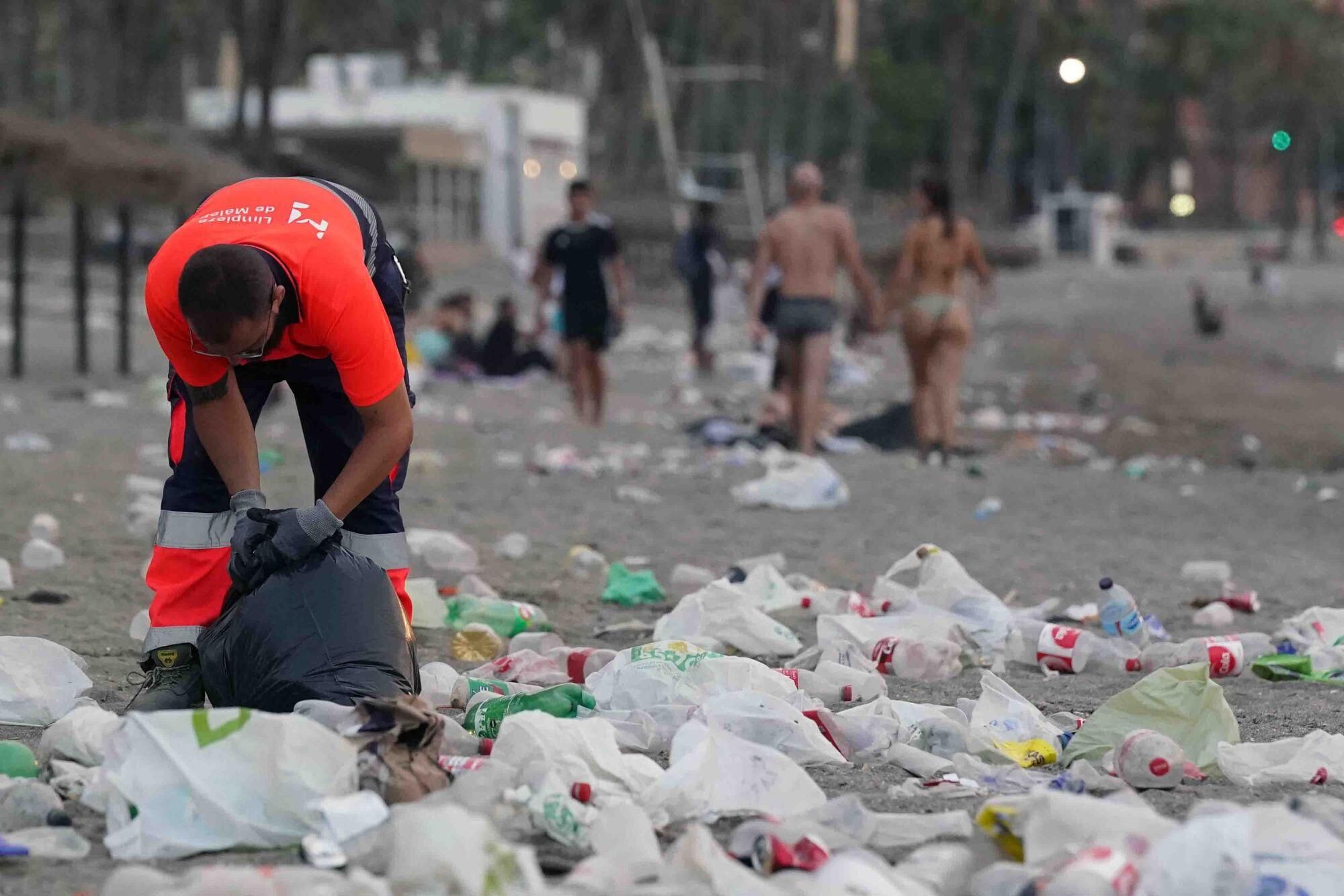 Varios operarios de la empresa de limpieza de Limasam, recogen los residuos de la playa de La Malagueta, tras la Noche de San Juan en Málaga 2025