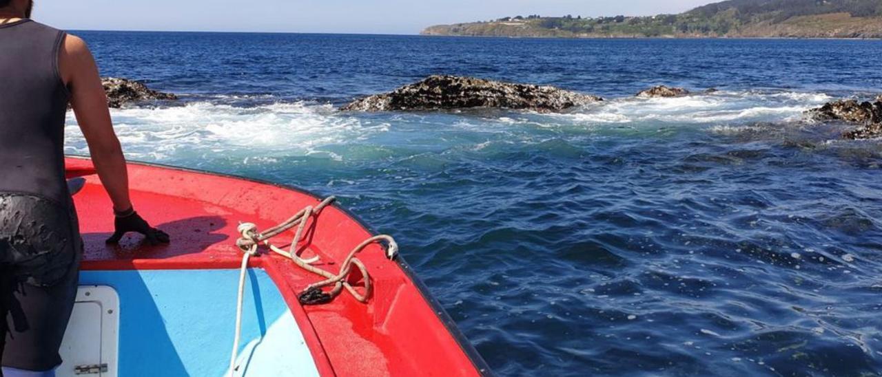 Un bateeiro dispuesto a saltar a las rocas para recoger mejilla. |   //  FDV