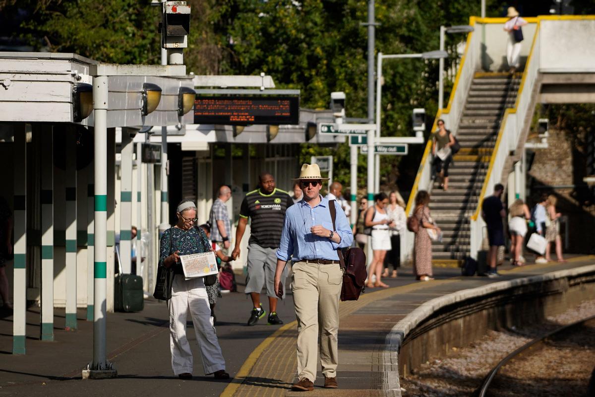 Viajeros esperan su tren en uno de los andenes de Victoria Station, en Londres, en un día de intensísimo calor en la ciudad.