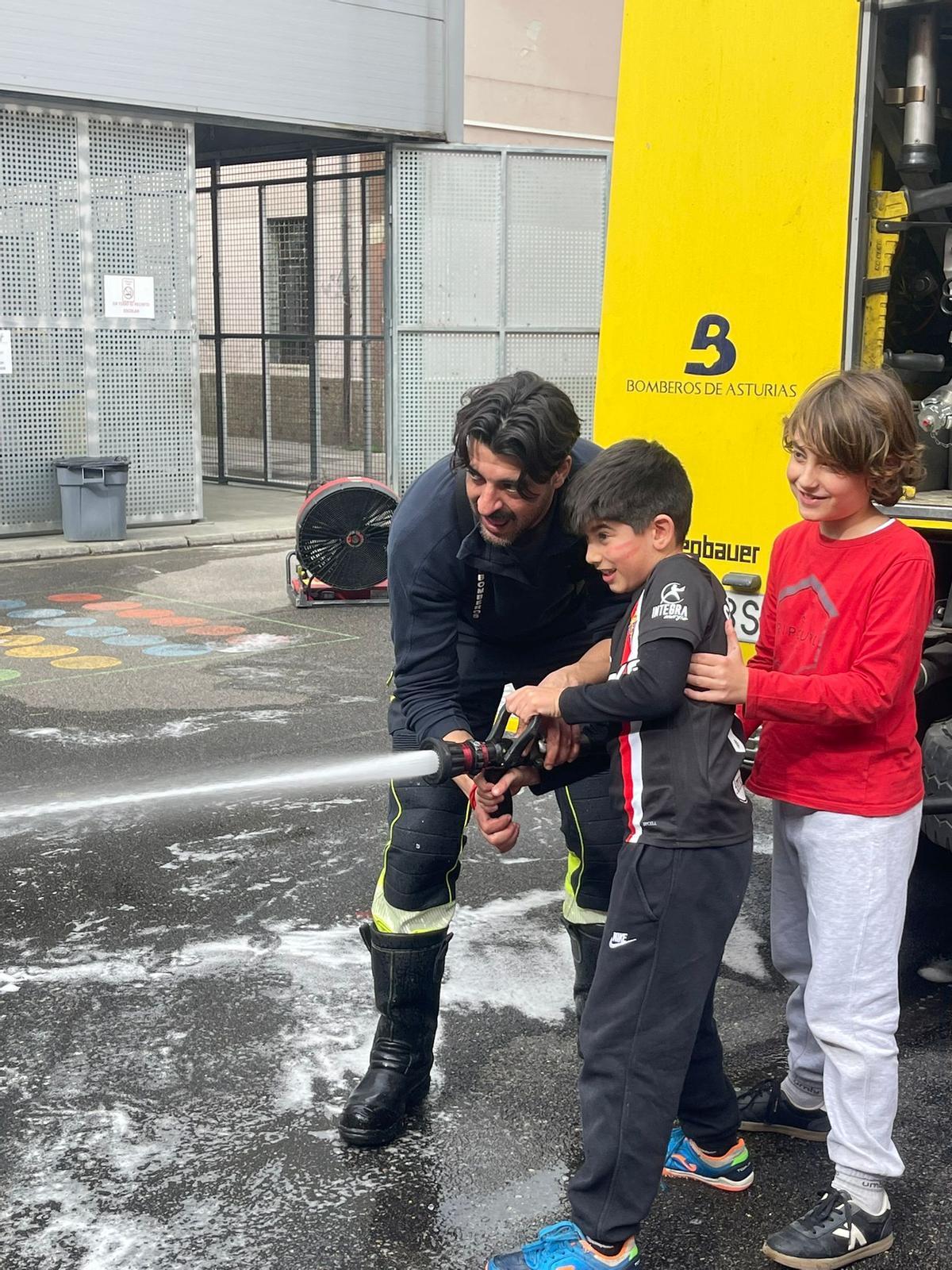 Un escolar, con la manguera del camión de bomberos.