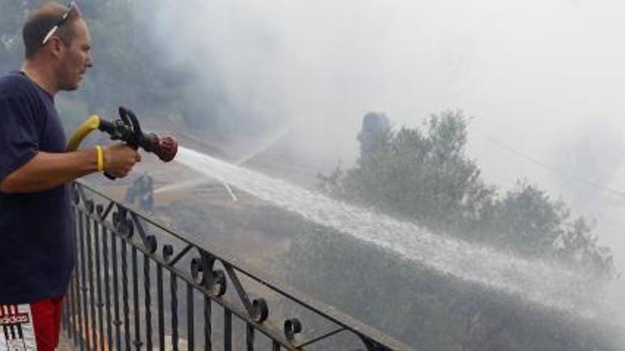 Un vecino de Carlet trata de apagar el fuego junto a su casa.