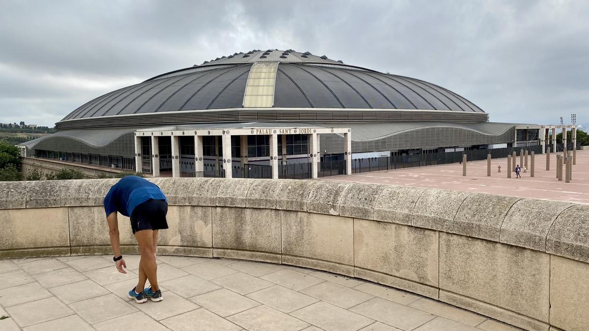 Un corredor realiza estiramientos, junto al Palau Sant Jordi, este lunes