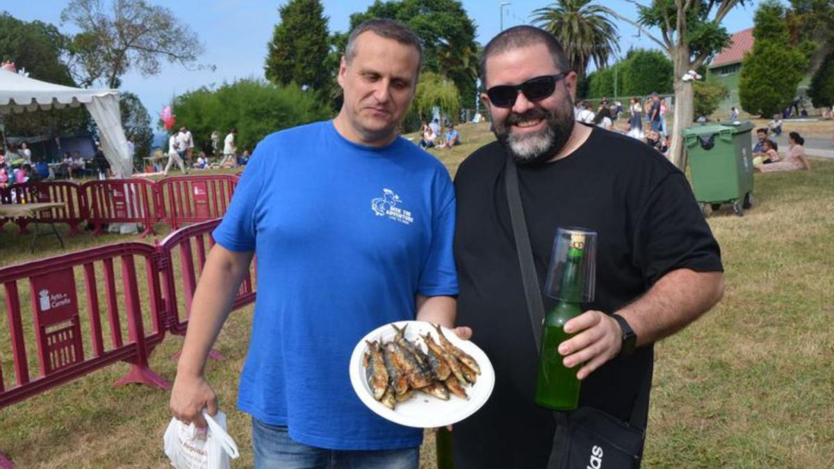 Dos amigos, con una ración de sardinas y una botella de sidra.