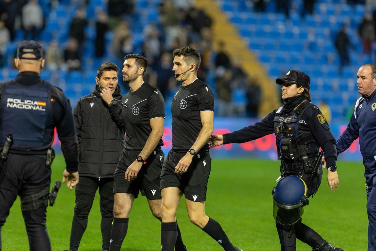 La Polícia escolta al colegiado Pablo Morales Moreno al final del Hércules-Sabadell tras suspender el partido 15 minutos.