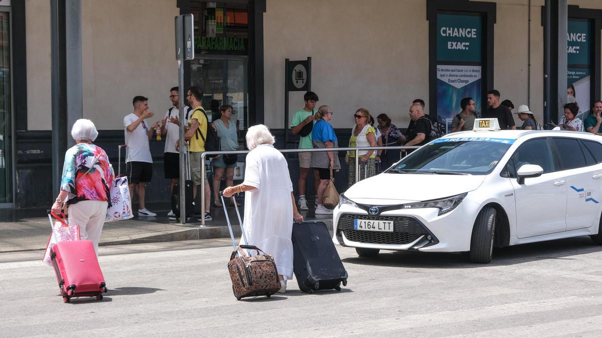 Varias personas esperan taxis en la parada de la estación de Renfe de Alicante.