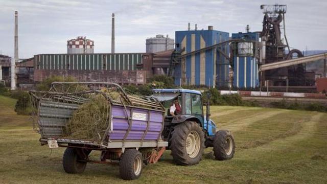 Labores agrícolas junto a las instalaciones de ArcelorMittal en Gijón. | JUAN PLAZA