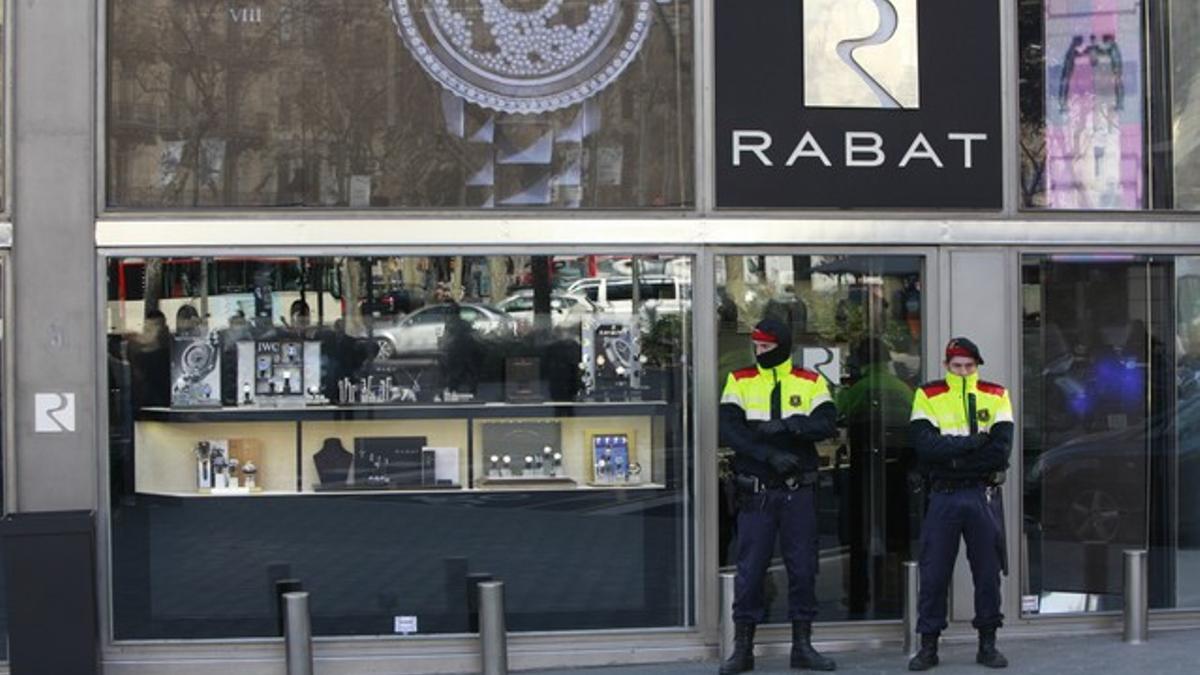 Dos mossos vigilan la entrada de la joyería Rabat durante el registro policial del establecimiento.