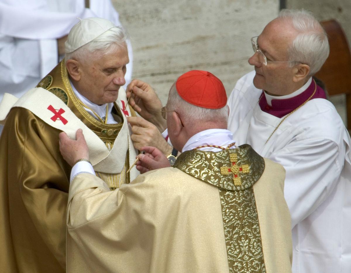 Benedicto XVI se coloca la insignia papal con la ayuda del obispo Piero Marini, en la plaza de San Pedro, el 24 de abril del 2005.