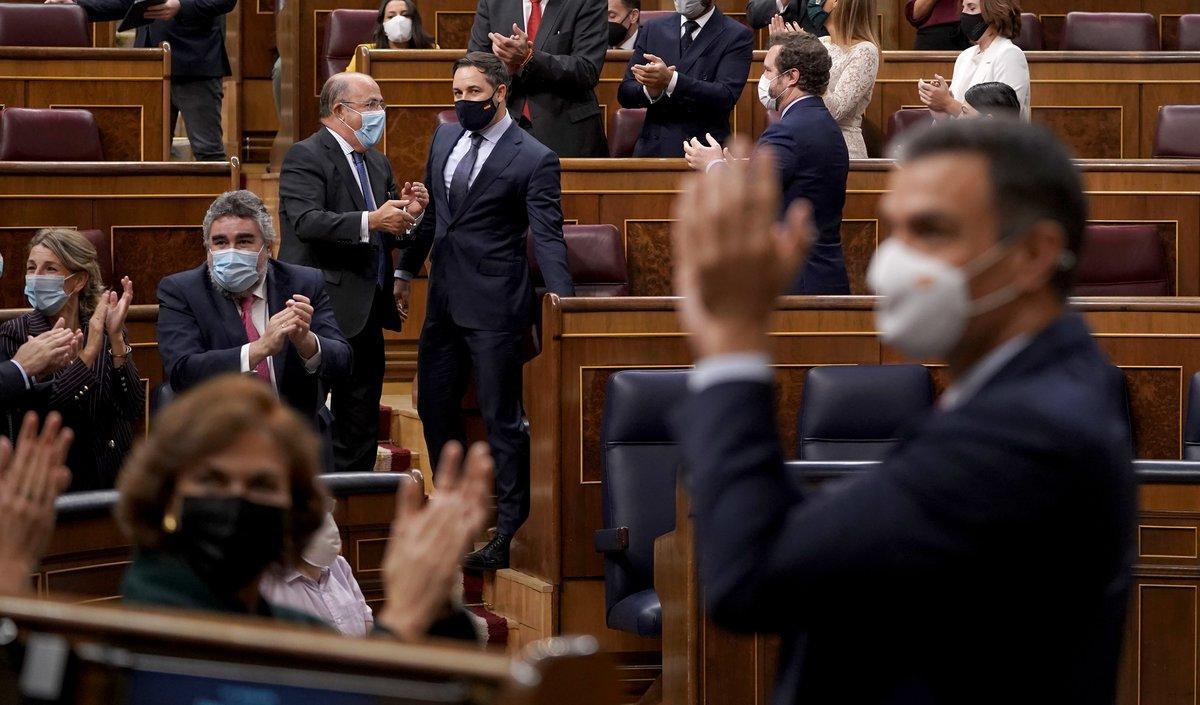 El presidente del Gobierno, Pedro Sánchez, aplaude el resultado de la moción de censura perdida por el líder de Vox, Santiago Abascal, al fondo, este 22 de octubre en el Congreso. 
