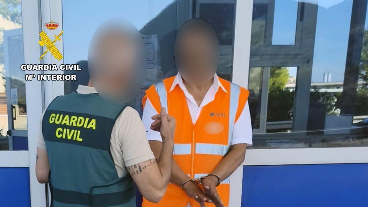 El sospechoso, esposado, cuando fue detenido por la Benemérita en su puesto de trabajo.