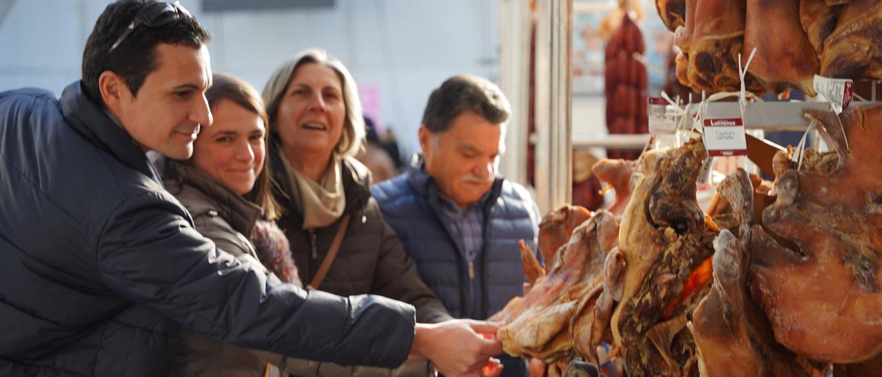 Varios clientes compran examinan carne de cerdo en un stand de la Carpa do Cocido.