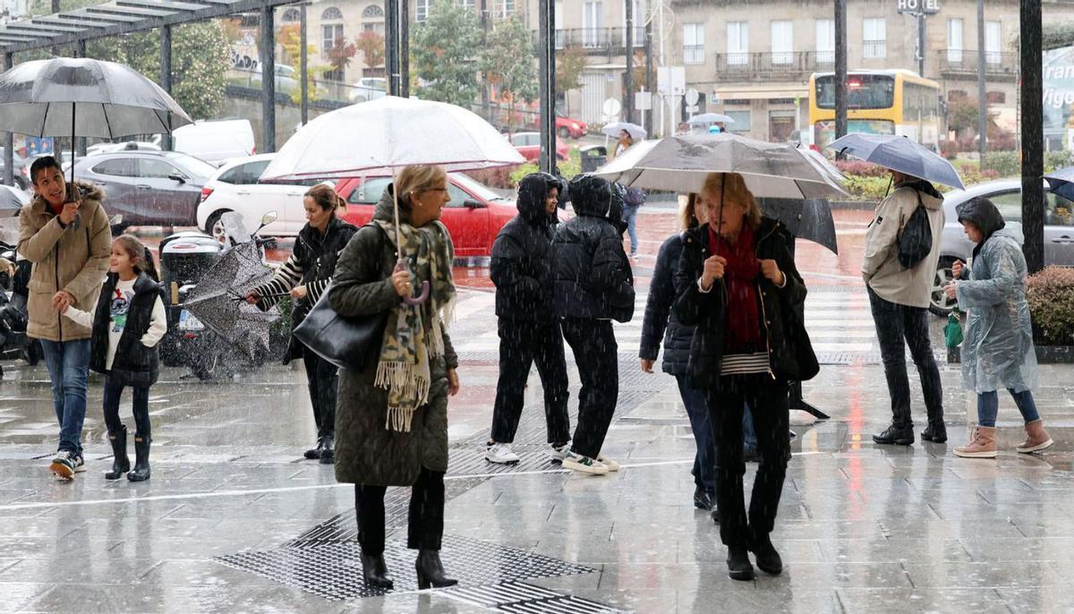 Un grupo de personas, con sus paraguas, ayer en Vigo, en el entorno de Vialia. |  // MARTA G. BREA